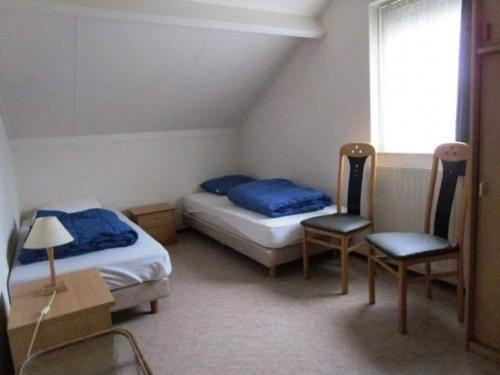 Una habitación con dos camas y una silla y una ventana. en Bungalow in Breskens near Beach & Lighthouse, en Breskens