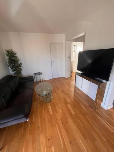 Il comprend un salon doté d'un canapé noir et d'une télévision à écran plat. dans l'établissement Grand appartement 4 personnes à 150m de la plage, au Barcarès