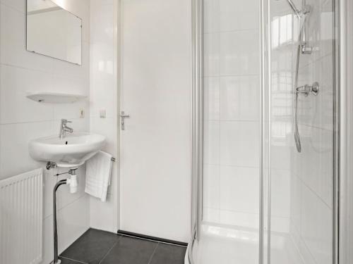 a white bathroom with a sink and a shower at Bungalow in South Holland with Private Jetty in Simonshaven