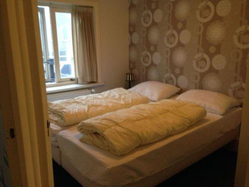 two beds sitting next to a window in a bedroom at Historic Cottage w Garden in Breskens