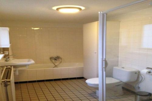 a bathroom with a tub and a toilet and a sink at Historic Cottage w Garden in Breskens