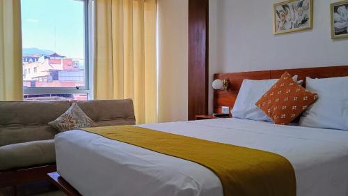 a bedroom with a bed and a couch and a window at Riosol Hotel Tarapoto in Tarapoto