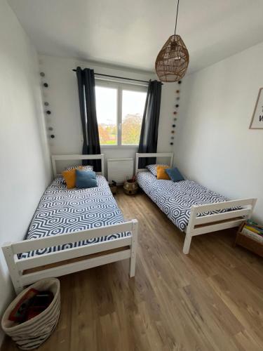 deux lits dans une chambre avec une fenêtre dans l'établissement Maola, calme et central, à Reims