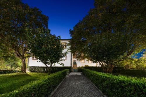 a walkway leading to a white house with trees at Solar das Tilias - Historic House in Seia