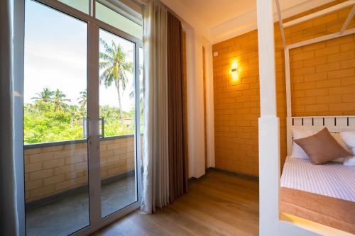 a bedroom with a bed and a large window at Bliss Blessings Villa & Spa - Hikkaduwa in Hikkaduwa