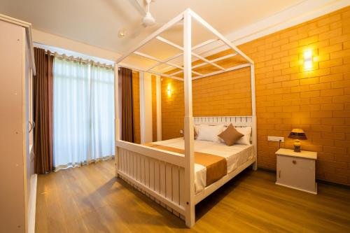 a bedroom with a canopy bed in a yellow brick wall at Bliss Blessings Villa & Spa - Hikkaduwa in Hikkaduwa