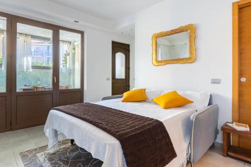 a bedroom with a bed with yellow pillows and a mirror at L'essenziale - Experience in Alba Free Park & WiFi in Alba