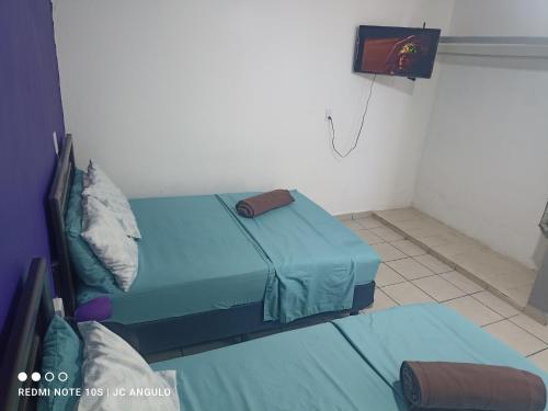 マサトランにあるCasa sencilla, primer piso bien ubicadaのベッドが2つと壁にテレビがある部屋