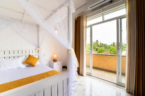a bedroom with a bed and a large window at Bliss Blessings Villa & Spa - Hikkaduwa in Hikkaduwa