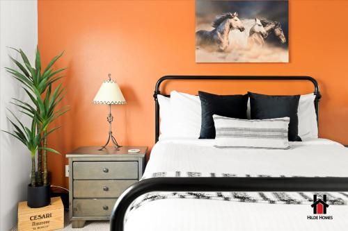 a bedroom with an orange wall with a bed and a lamp at Sonoran Desert Getaway with Cowboy Tub in Cave Creek