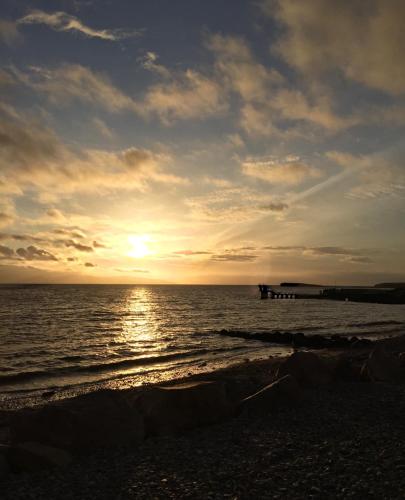 a sunset on the beach with a pier in the water at The Parlour Cottage in Galway