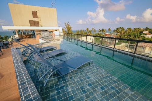 a swimming pool with lounge chairs on top of a building at Aconchego, varandinha e vista mar em Maracaípe in Porto De Galinhas