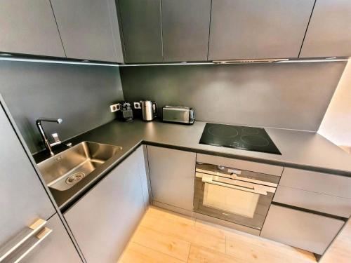 une petite cuisine avec un évier et une cuisinière dans l'établissement Résidence Le Stella - Appartement lumineux avec jardin privé au centre MAE-2601, aux Gets