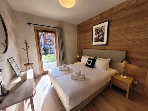 une chambre avec un grand lit blanc avec une fenêtre dans l'établissement Résidence Le Stella - Appartement lumineux avec jardin privé au centre MAE-2601, aux Gets