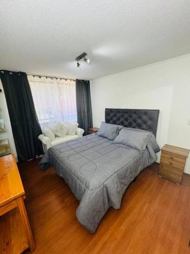 a bedroom with a large bed and a chair at Dpto, Bar y con Estacionamiento in Santiago