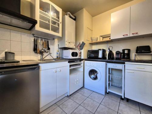 une cuisine avec des armoires blanches et une laveuse et une sécheuse dans l'établissement Residence Du Temple - Agréable studio, très fonctionnel et bien agencé ! MAE-7124, à Aix-les-Bains