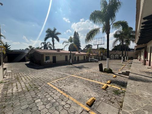a parking lot with a building and palm trees at Hotel Posada Virreyes in Guadalajara