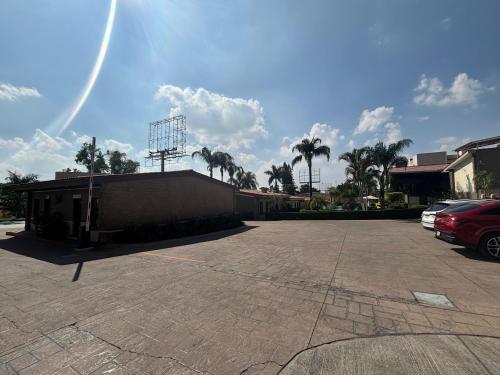 a parking lot with a building and palm trees at Hotel Posada Virreyes in Guadalajara