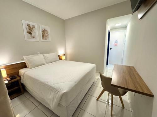 a hotel room with a bed and a desk and a table at Hotel Arrastão in São Sebastião
