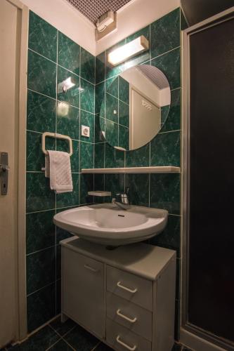 a green tiled bathroom with a sink and a mirror at Baki Portorose in Portorož