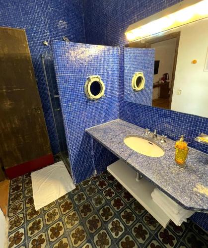a blue tiled bathroom with a sink and a mirror at Hotel Casa Paradiso Guarujá in Guarujá