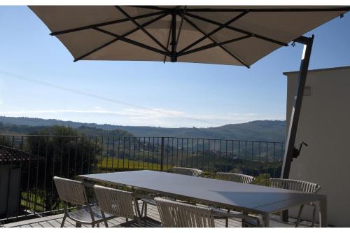 a table and chairs on a balcony with an umbrella at Casa Schiavenza Perno in Monforte dʼAlba