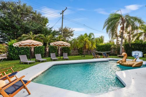 a swimming pool with chairs and umbrellas in a yard at Centrally Located 4BD Oasis with Pool & Movie Patio in Hollywood