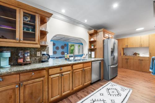 a kitchen with wooden cabinets and a stainless steel refrigerator at Centrally Located 4BD Oasis with Pool & Movie Patio in Hollywood