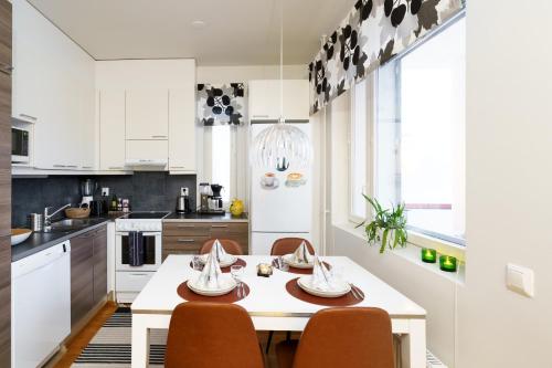 una cucina bianca con tavolo e sedie di Adorable Arctic Apartments - Private Sauna & Free Parking a Rovaniemi
