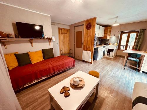 a living room with a red couch and a table at Le Dune Logement in Le Bourg-dʼOisans