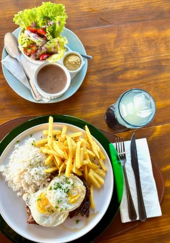 two plates of food with eggs rice and french fries at Hotel Casa Paradiso Guarujá in Guarujá