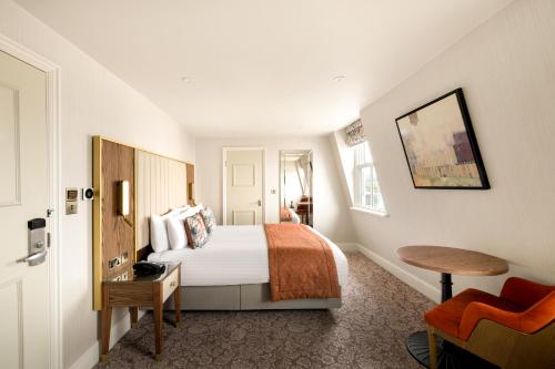 a hotel room with a bed and a chair at voco The Clifton Folkestone by IHG in Folkestone