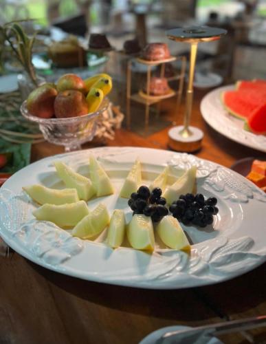 a white plate with fruit on a wooden table at Hotel Casa Paradiso Guarujá in Guarujá