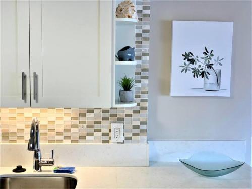 a kitchen with white cabinets and a sink and plants at 1519 Ilikai Collection 9 Beachfront Resort recently upgraded in Honolulu