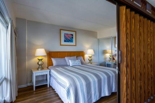a bedroom with a bed with two tables and two lamps at 1519 Ilikai Collection 9 Beachfront Resort recently upgraded in Honolulu