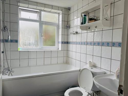 a bathroom with a tub and a toilet and a sink at Bella Homes-Spacious 4 bedroom Modern Town house Romford in Romford