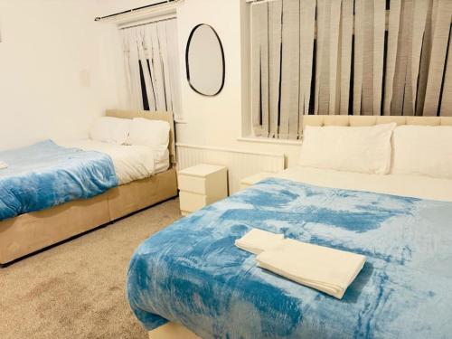 a bedroom with two beds and a mirror at Bella Homes-Spacious 4 bedroom Modern Town house Romford in Romford