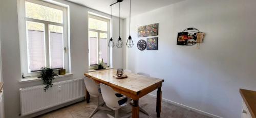 a dining room with a wooden table and two windows at Ferienwohnung am Stadtrand in Eisenach