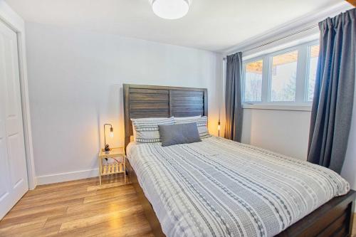 a bedroom with a bed with a wooden headboard and windows at La Petite Ourse - boisé avec spa in Petite-Rivière-Saint-François