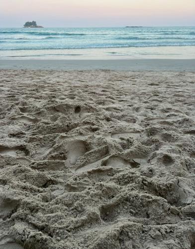 a sandy beach with footprints in the sand at Hotel Casa Paradiso Guarujá in Guarujá