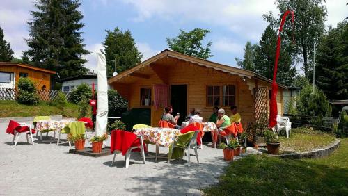 Un groupe de personnes assises à des tables devant une maison dans l'établissement Pilger-Hüttli - Blockhaus, à Schönengrund