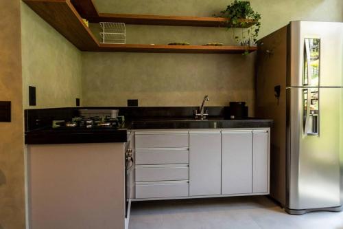 a kitchen with a sink and a refrigerator at Star Green 211 - Triplex com linda vista e ótima localização in Campos do Jordão