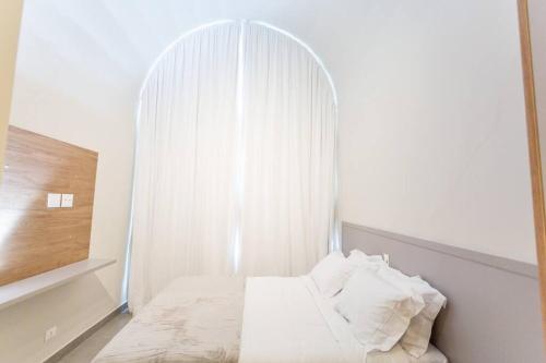 a bedroom with a bed with an arched window at Star Green 211 - Triplex com linda vista e ótima localização in Campos do Jordão