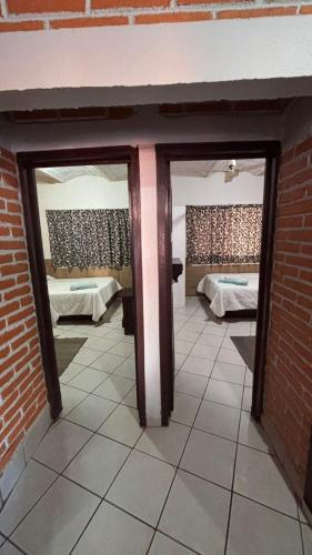 a room with two beds and two glass doors at Bungalows Flamingos in Rincon de Guayabitos