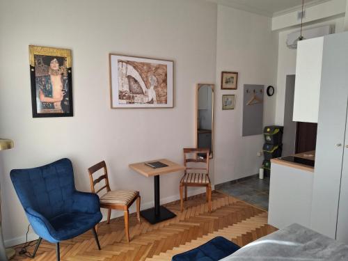 a living room with a blue chair and a table at Apartament studio z widokiem na Rynek in Bochnia