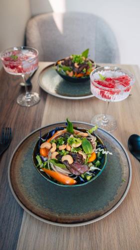 a table with two plates of food and two wine glasses at Night & Day lodge - glass roof with hot tub in Reykholt