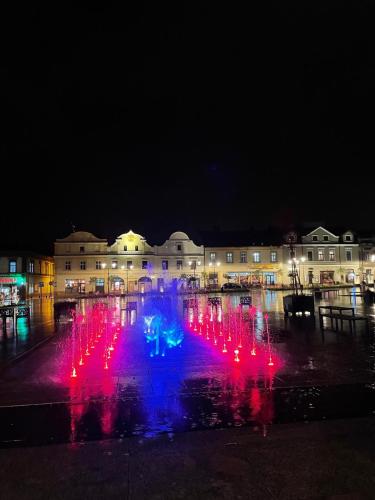 a fountain with red and blue lights in front of a building at Apartament studio z widokiem na Rynek in Bochnia