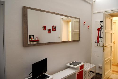 a mirror on a wall above a desk with a television at Alloggio turistico in Pisa