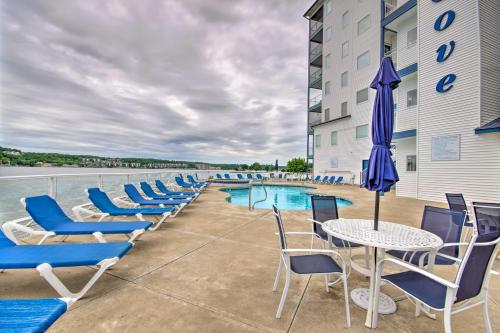 a patio with chairs and a table with an umbrella at Sunshine Shack Lake Ozark Condo Pool, Lake View in Lake Ozark