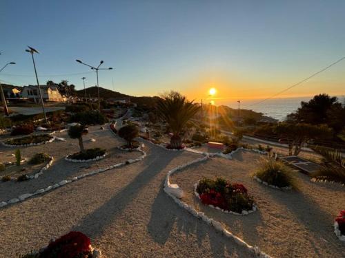 a sunset over a park with flowers and the ocean at Cabaña Vista Mar in Tongoy